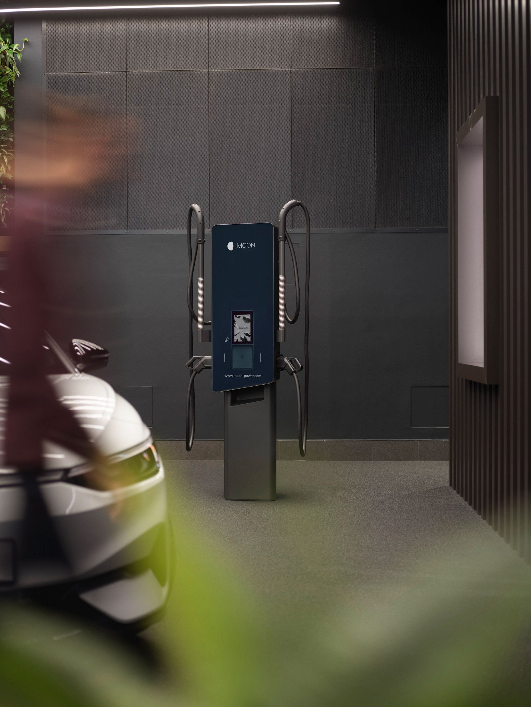 Stația de încărcare într-o cameră cu pereți gri și o mașină în prim-plan