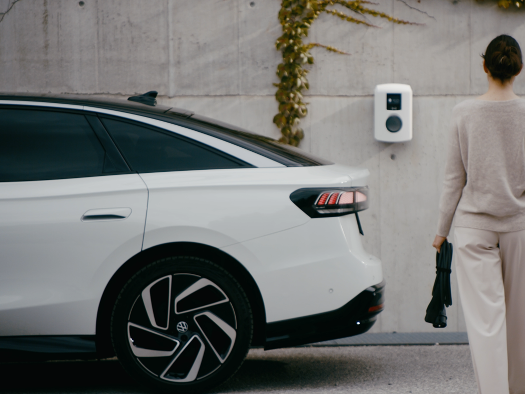 O femeie merge spre o stație de încărcare de pe un perete