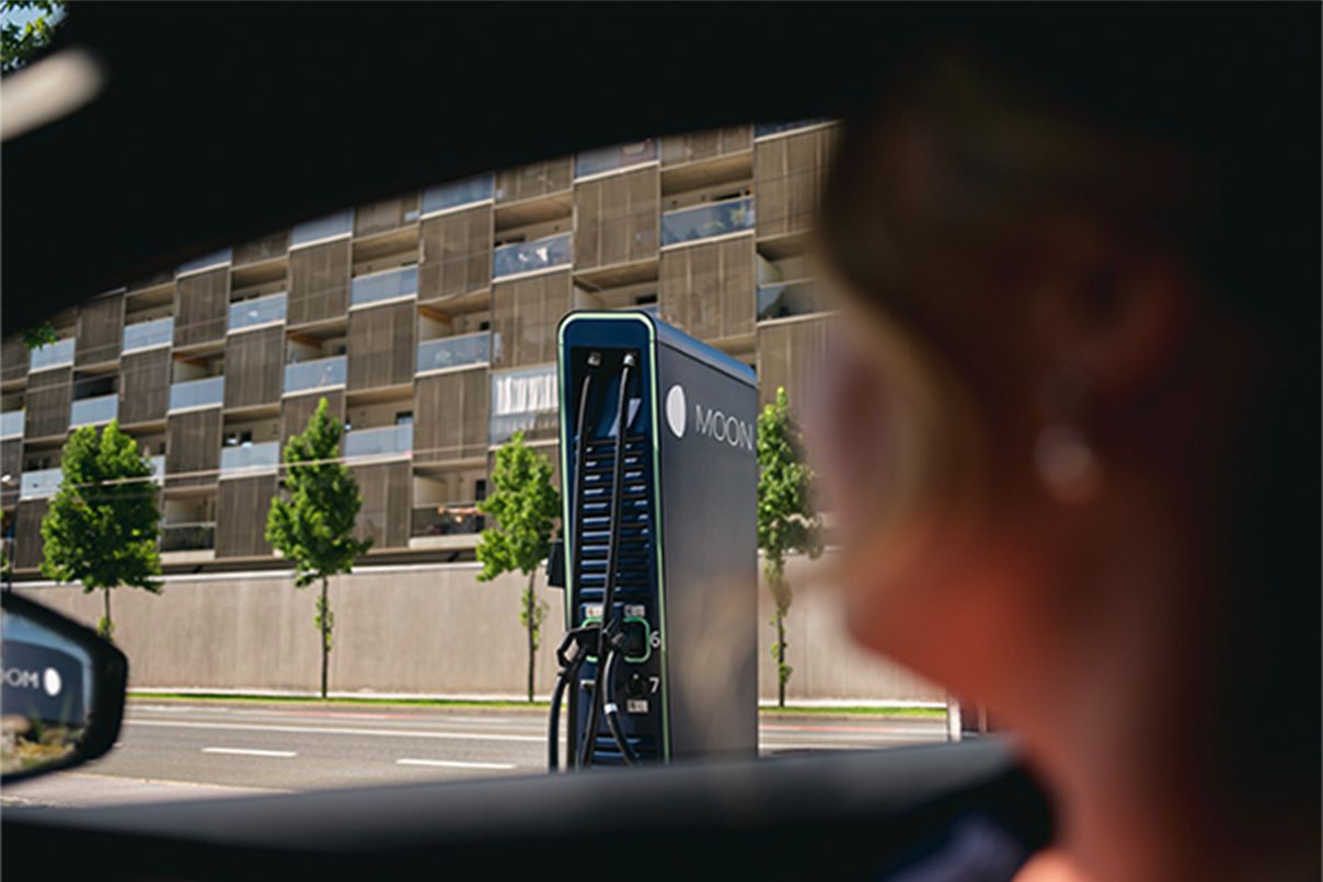 Persoană stând într-o mașină cu stația de încărcare în fundal