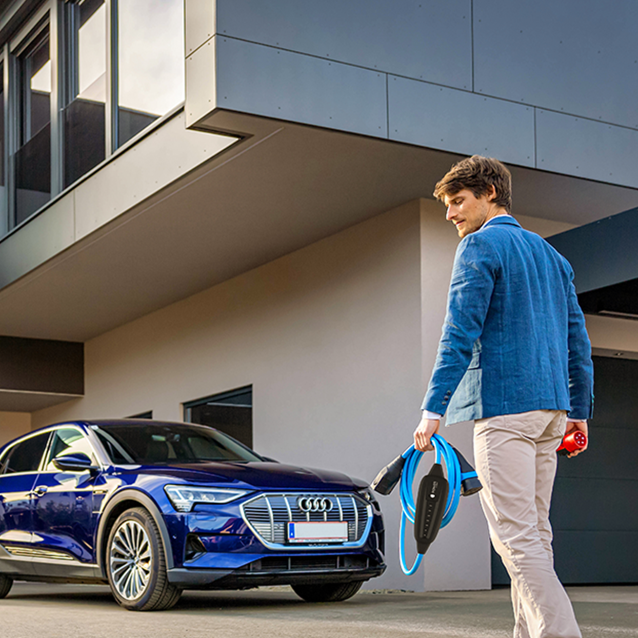 O persoană merge spre o mașină cu cablu în mână