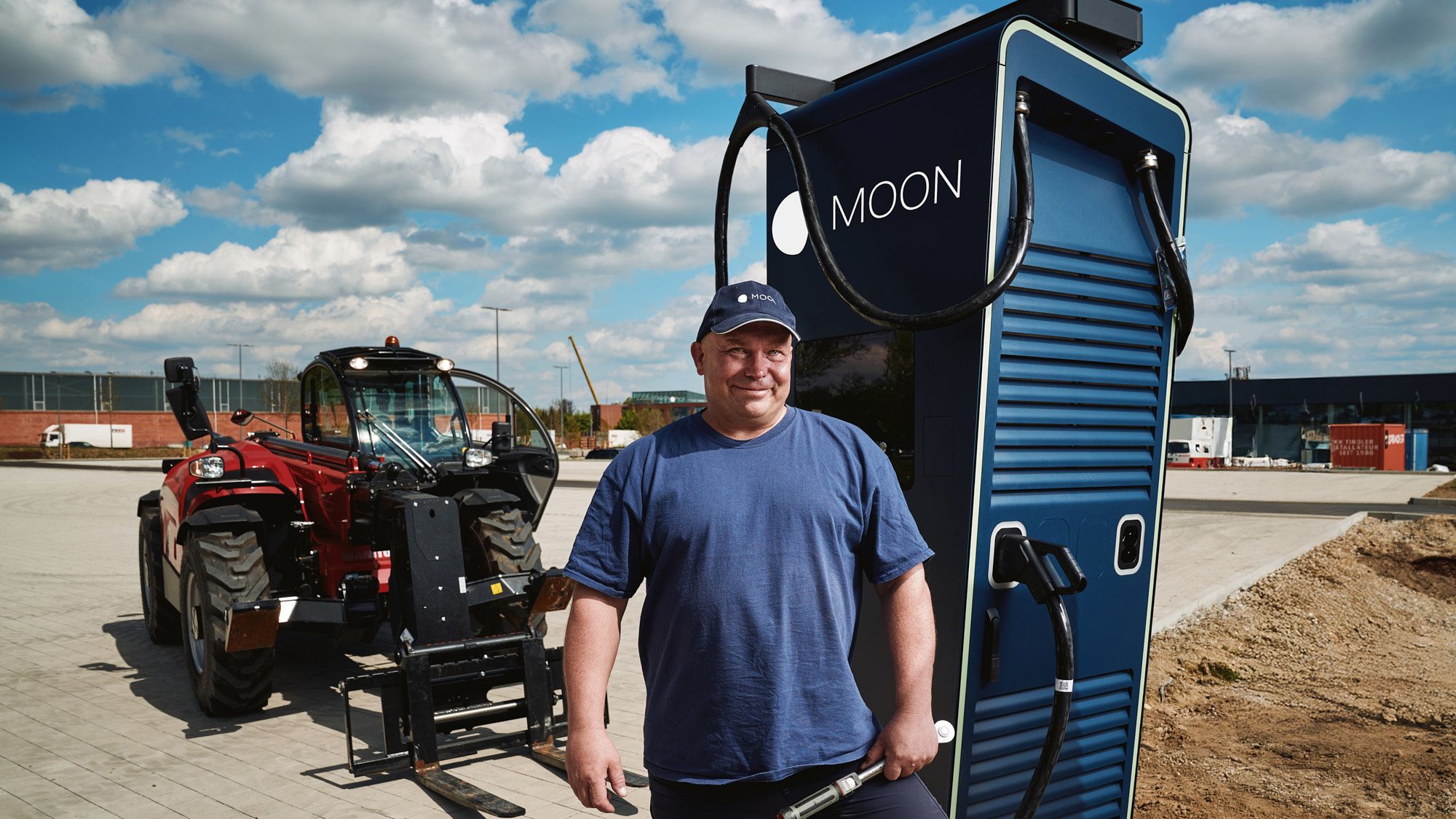 A man stands in front of the POWER Charger fast charging station