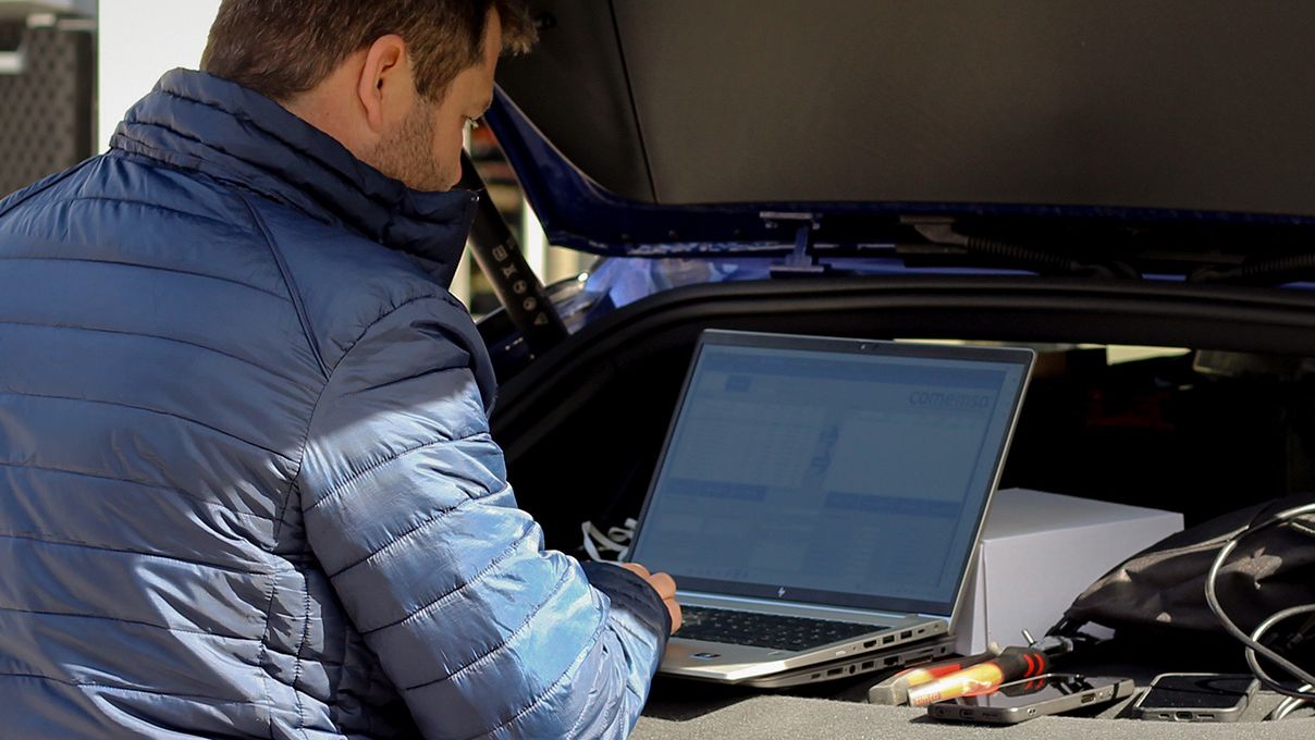 Bărbat cu laptopul stând pe coperta unui portbagaj